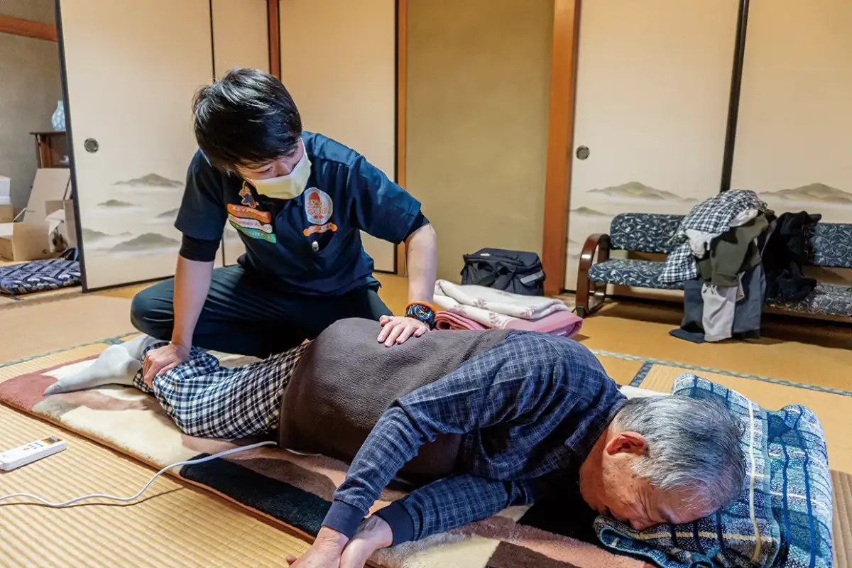 自宅で腰の訪問マッサージを受ける男性