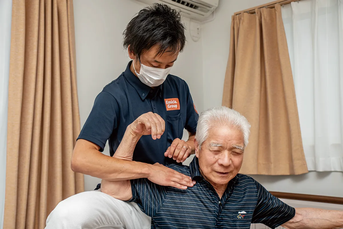 訪問マッサージで肩の施術を受ける高齢男性